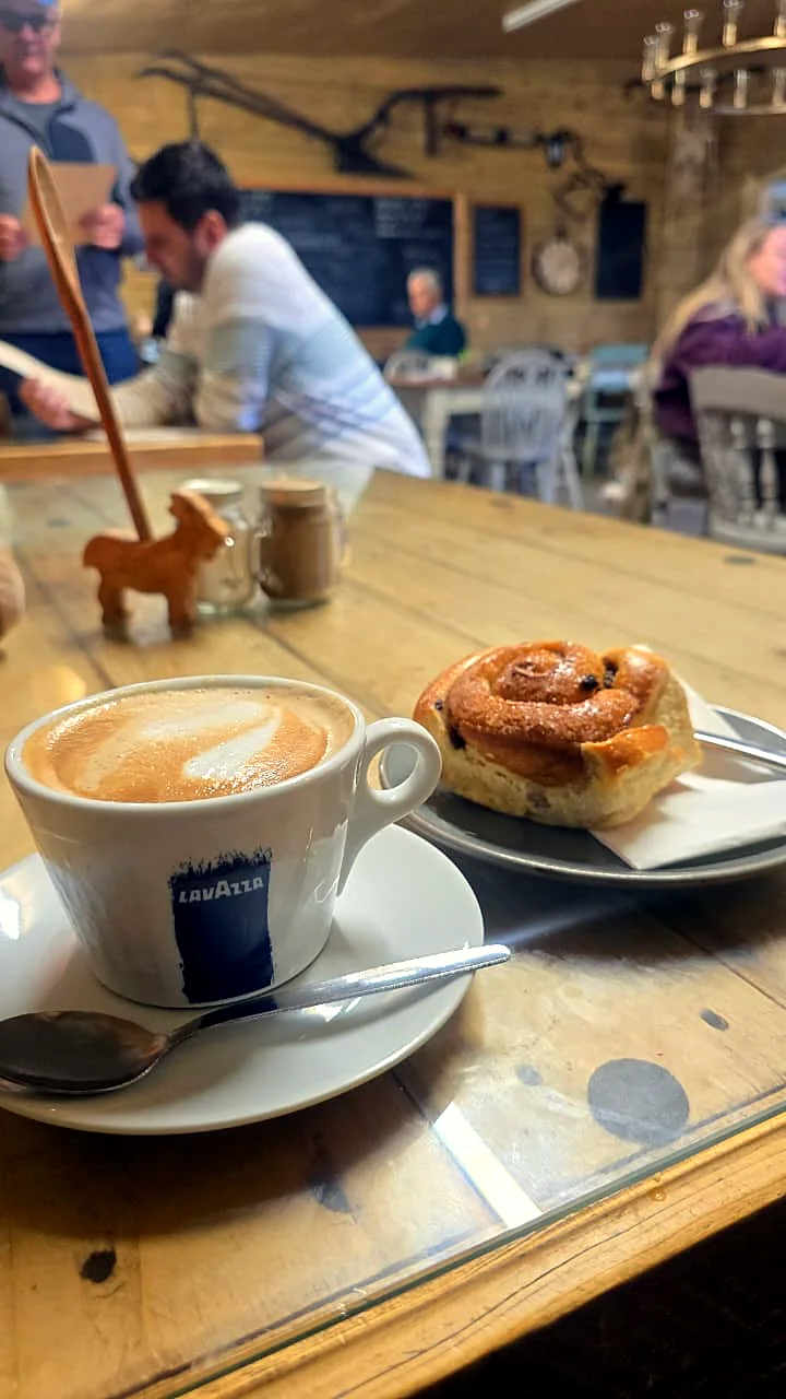 A flat white and a cinnamon bun on a café table.