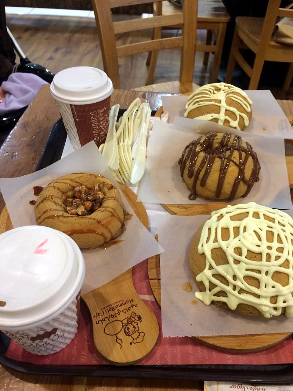Frosted buns and coffees on a café table.