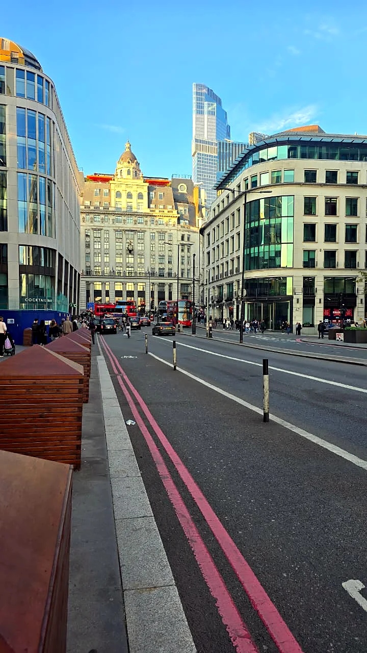 A London street with a red bus lane between tall buildings.